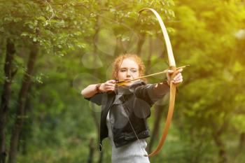 Sporty young woman practicing archery outdoors�