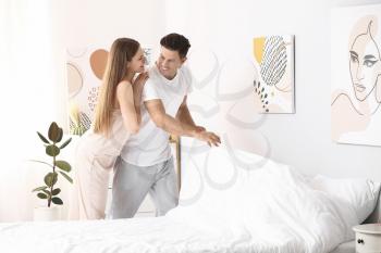 Morning of happy young couple changing bedclothes at home�