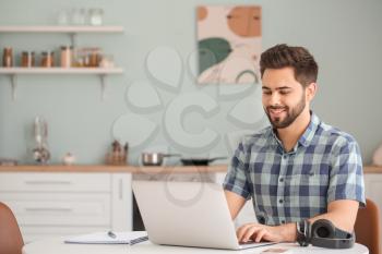 Young man using laptop for online learning at home�