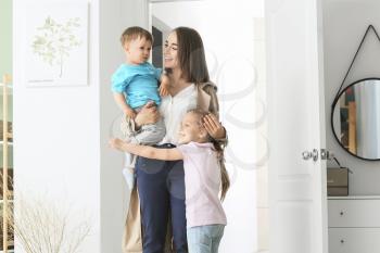 Happy children meeting their mother after work at home�