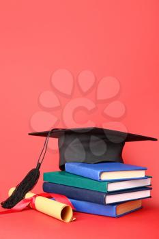 Graduation hat, diploma and books on color background�