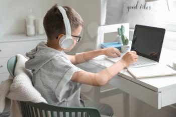 Cute little boy using laptop at home�