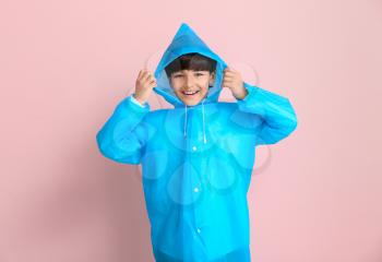 Cute little boy in raincoat on color background�