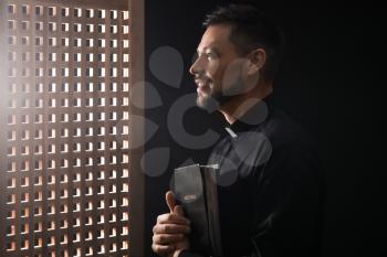 Male priest in confession booth�