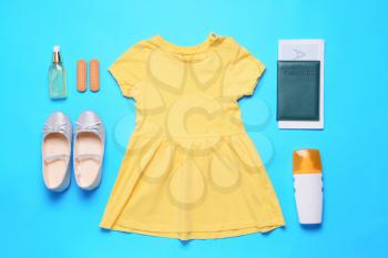 Flat lay composition with little girl dress and accessories on color background. Travel concept�