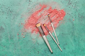 Makeup brushes and cosmetics on color background�