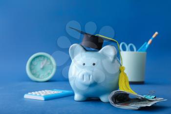 Piggy bank with graduation hat and money on color background. Tuition fees concept�