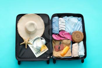 Packed suitcase with beach accessories on color background. Travel concept�