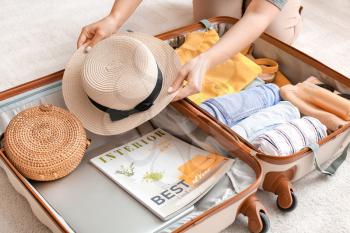 Woman packing suitcase at home. Travel concept�