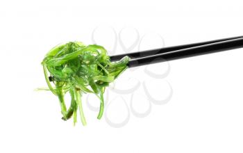 Chopsticks with tasty seaweed salad on white background�