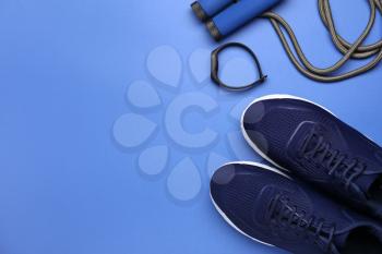 Sportive shoes and jumping rope on color background�