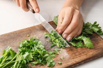 Woman cutting fresh parsley at table, closeup�