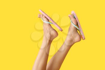 Legs of young woman in flip-flops on color background�