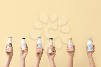 Female hands with bottles of vegan milk on color background�
