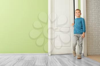 Cute little boy opening door in room�