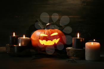 Carved Halloween pumpkin and candles on dark background�