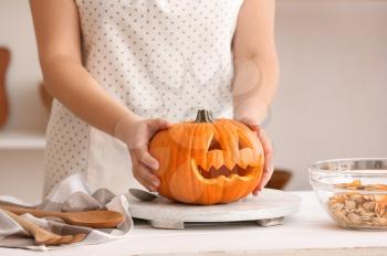 Woman carving pumpkin for Halloween at table�