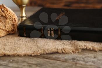 Holy Bible with bread on wooden table�