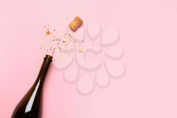 Bottle of champagne and glitters on color background. New year celebration�