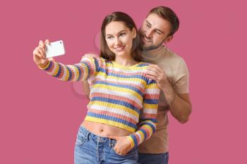 Young couple taking selfie on color background�