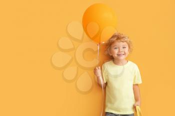 Cute little boy with air balloon on color background�