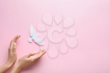 Female hands with paper dove on color background. International Day of Peace�