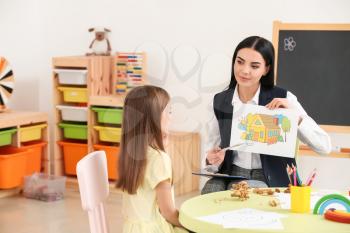 Female psychologist working with little girl at home�