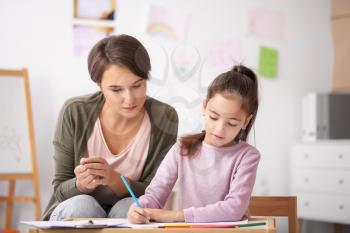 Female psychologist working with little girl at home�