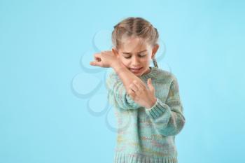 Allergic little girl scratching herself on color background�
