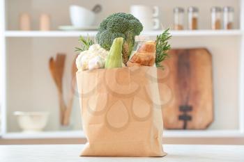 Paper bag with different products on table in kitchen�
