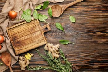 Cutting board with herbs and spices on wooden background�