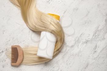 Bottle of shampoo, comb and hair strand on light background�