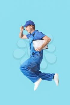 Jumping male worker on color background�