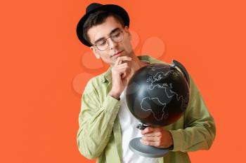 Male tourist with globe on color background�