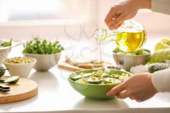 Woman making salad with fresh vegetables in kitchen�