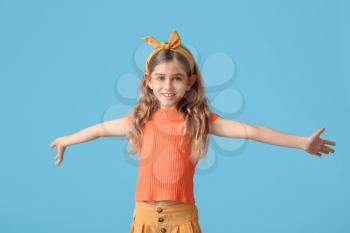 Little girl opening arms for hug on color background�