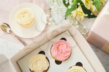 Composition with tasty cupcakes and flowers on light background, closeup�