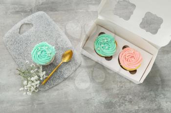 Composition with tasty cupcakes and flowers on light background�