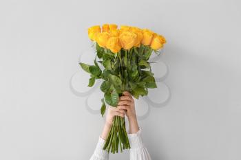 Female hands with beautiful yellow roses on light background�