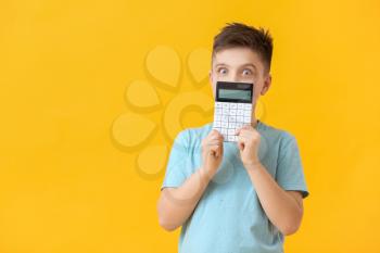 Surprised little boy with calculator on color background�