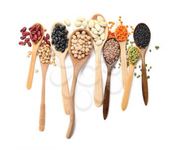 Spoons with different legumes on white background�