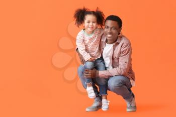 Portrait of happy African-American father and his little daughter on color background�