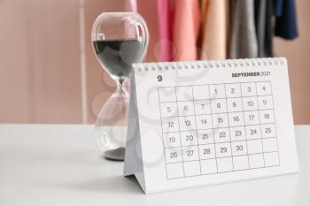 Flip paper calendar with hourglass on table in office�