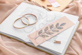 Book with bookmark and earrings on color background�