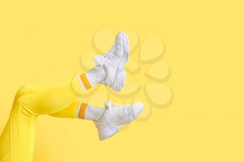 Legs of stylish young woman in leggings on yellow background�
