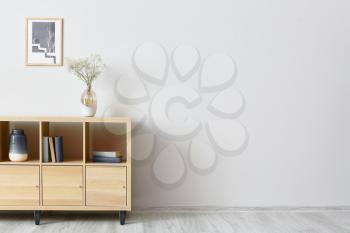 Modern chest of drawers with decor near light wall�
