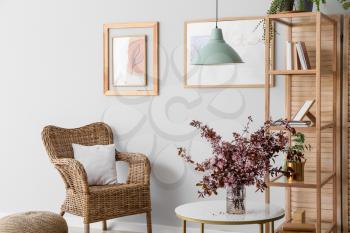 Vase with blossoming branches on table in interior of living room�