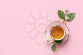 Cup of jasmine tea and flowers on color background�