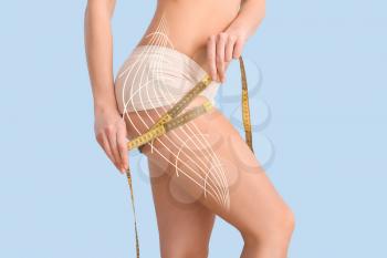 Young woman with measuring tape on color background. Concept of cellulite�