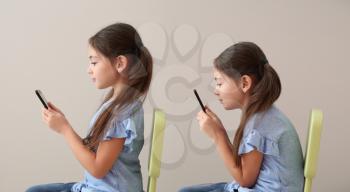 Little girl with bad and proper posture using mobile phone on grey background�